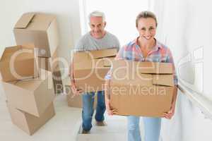 Happy couple carrying cardboard moving boxes