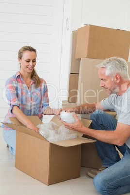 Happy couple unpacking cardboard moving boxes