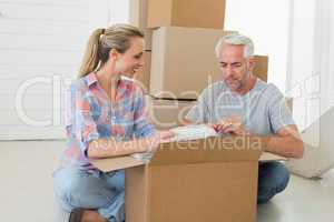 Happy couple unpacking cardboard moving boxes