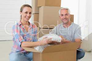 Happy couple unpacking cardboard moving boxes