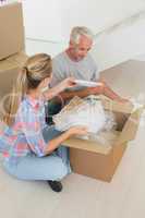 Happy couple unpacking cardboard moving boxes