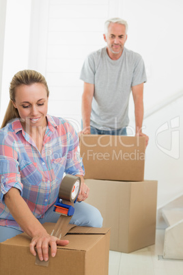 Happy couple sealing cardboard moving boxes