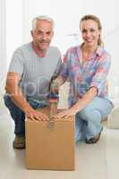 Happy couple sealing cardboard moving boxes