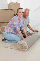 Happy couple rolling out new rug