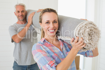Happy couple carrying a rolled up rug together