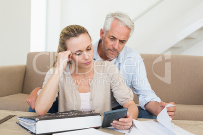 Serious couple calculating their bills at the couch