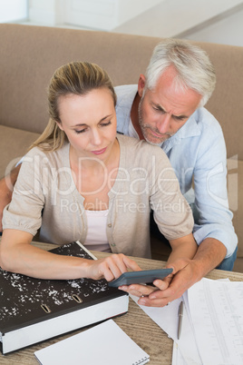 Serious couple calculating their bills at the couch