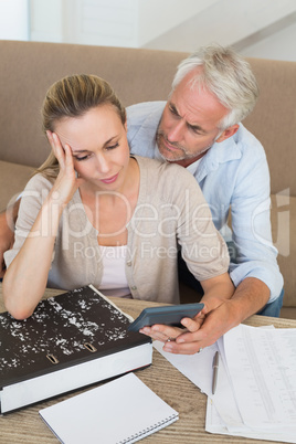 Serious couple calculating their bills at the couch