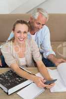 Smiling couple calculating their bills at the couch