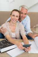 Smiling couple calculating their bills at the couch