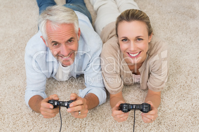 Smiling couple lying on rug playing video games