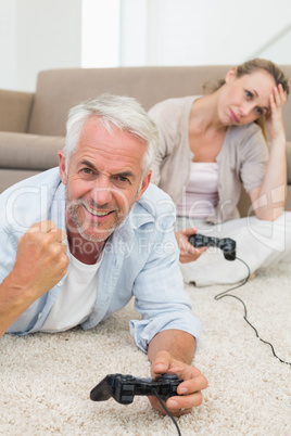 Smiling couple lying on rug playing video games