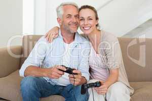 Happy couple having fun on the couch playing video games
