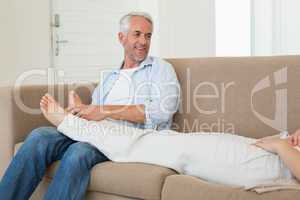 Caring man giving his partner a foot rub on the couch