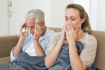 Sick couple sitting on the couch under a blanket