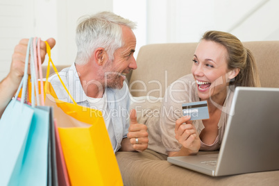 Happy couple shopping online on the couch