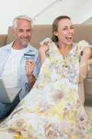 Happy couple shopping online on the couch