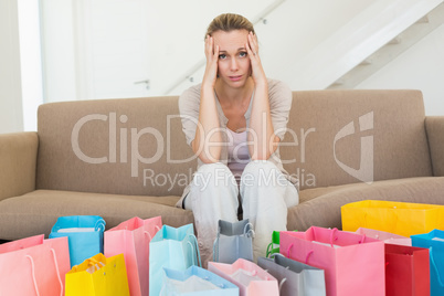 Regretful woman looking at many shopping bags on the couch