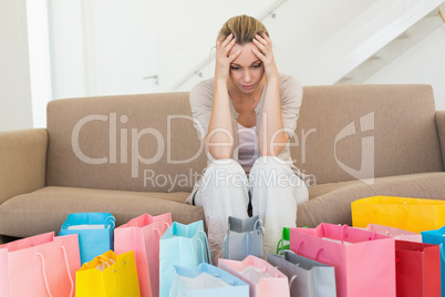 Regretful woman looking at many shopping bags on the couch