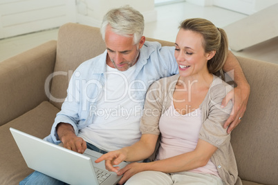 Happy couple using the laptop together on the couch