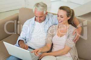 Happy couple using the laptop together on the couch