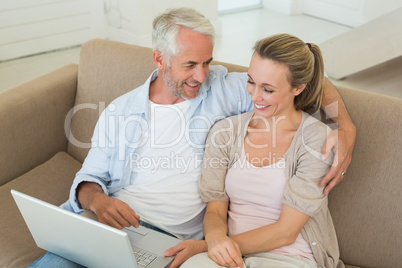 Happy couple using the laptop together on the couch