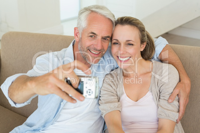 Happy couple taking a selfie together on the couch