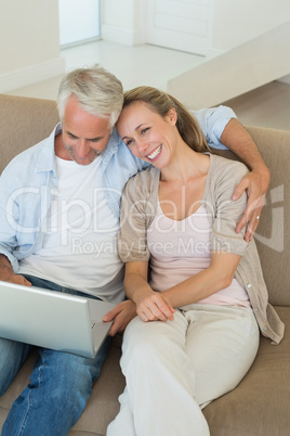 Happy couple using the laptop together on the couch