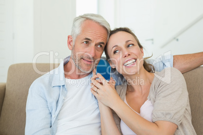 Happy couple listening to phone call together on the couch