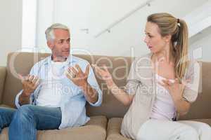 Angry couple sitting on couch arguing