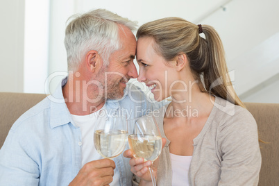 Happy couple sitting on couch toasting with white wine