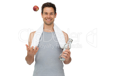 Smiling fit young man with apple and water bottle