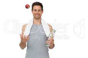 Smiling fit young man with apple and water bottle