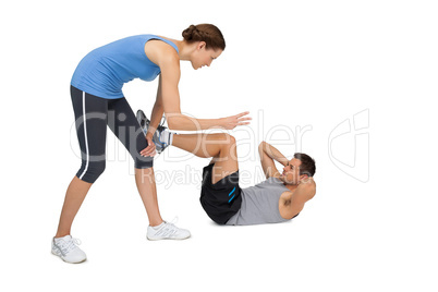 Female trainer assisting man with crunches