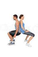 Side view of a fit young couple doing squats