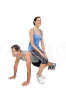 Female trainer sitting on man as he does push ups