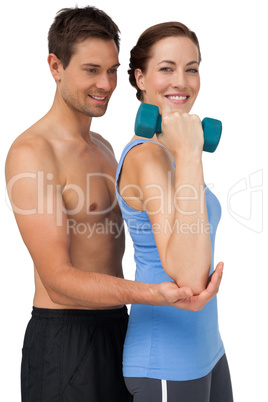 Male trainer assisting woman with dumbbell