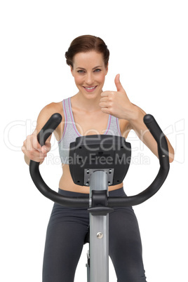Beautiful woman gesturing thumbs up on stationary bike