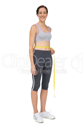 Full length portrait of a fit woman measuring waist