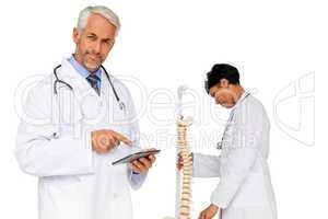 Doctor holding digital table with colleague by skeleton model