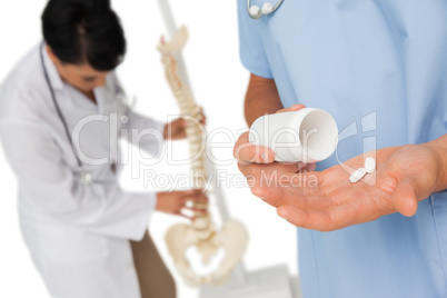 Mid section of doctors with pills and skeleton model