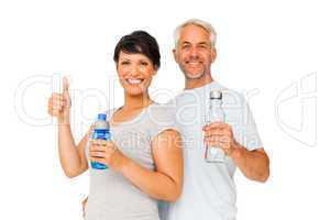 Fit couple with water bottles gesturing thumbs up