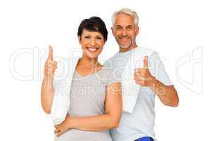 Portrait of a happy fit couple gesturing thumbs up