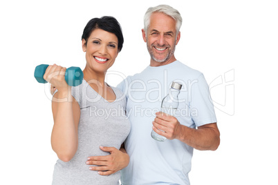 Happy fit couple with dumbbell and water bottle