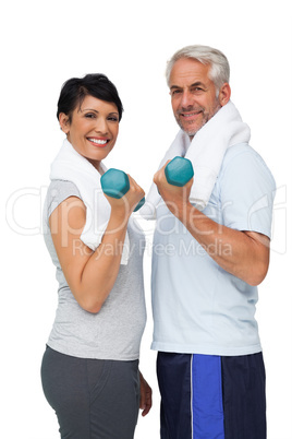 Portrait of a fit mature couple exercising with dumbbells