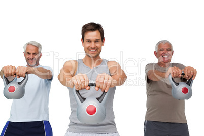 Portrait of three men exercising with kettle bells