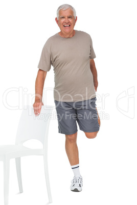 Full length portrait of a happy senior man stretching leg