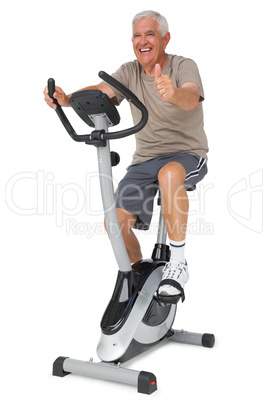 Senior man gesturing thumbs up on stationary bike