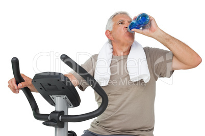 Senior man drinking water on stationary bike