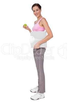 Young woman with weight scale and apple